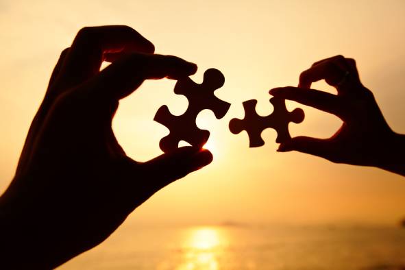 Man and woman hands trying to connect puzzle pieces